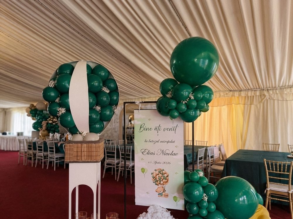 Decor de botez într-un cort alb, cu baloane verde închis și panou de bun venit
